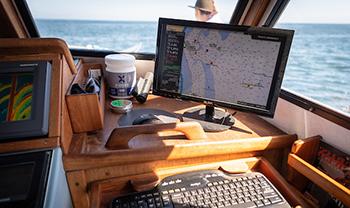 looking out to ocean from boat cockpit, a screen shows tides with numbers
